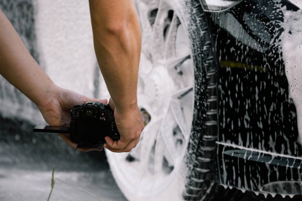 A person photographing the wheels of a car at the carwash