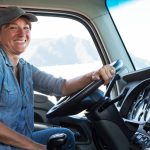 Caucasian woman truck driver in the cab of her commercial truck at a truck stop