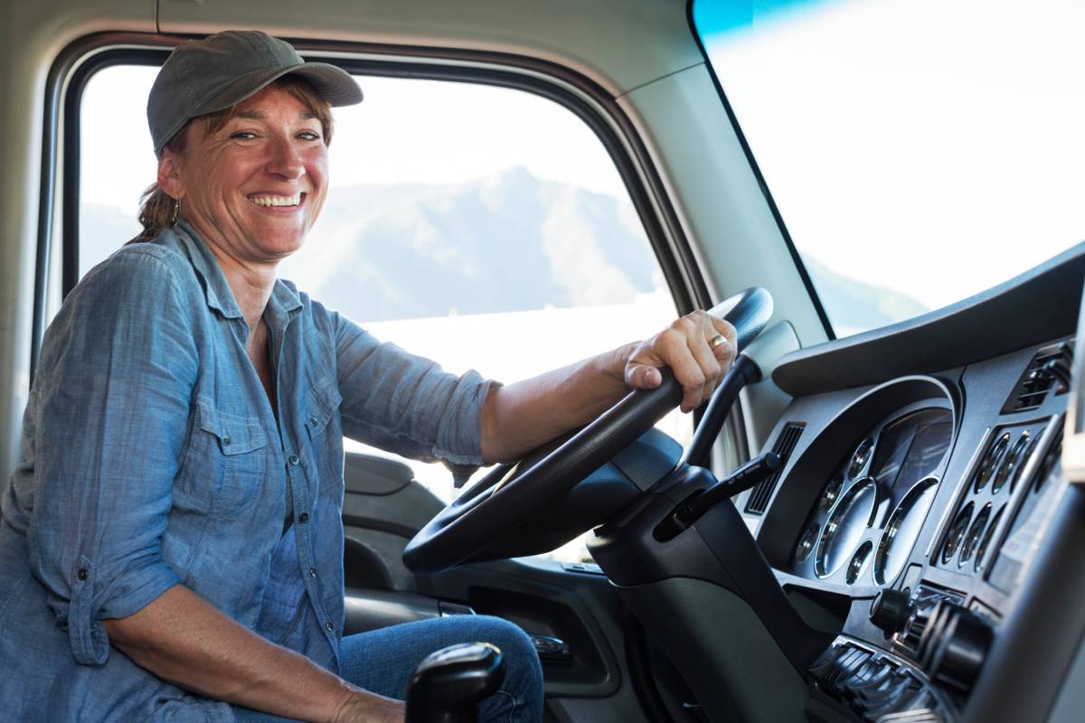 Caucasian woman truck driver in the cab of her commercial truck at a truck stop