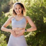 Shot of a young woman holding a heart on her tummy during a workout.